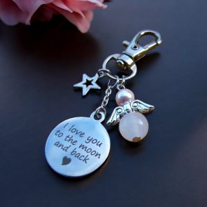 Donkerzilverkleurige sleutelhanger met een beschermengeltje van rozenkwarts en een Swarovski parel, plus een ster bedel en een 'I love you to the moon and back' bedel.