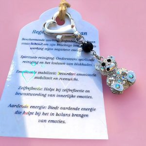 Tassenhanger met een donkerzilverkleurige beer bedel met rhinestone steentjes, een regenboog obsidiaan kraal en een kaartje met de werking van de steen.