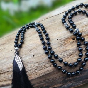 Lange mala ketting met 108 onyx kralen en zwart kwastje met donkerzilveren veertje.