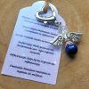 Donkerzilverkleurige hartvormige tassenhanger met beschermengel van lapis lazuli en bergkristal kraal en kaartje met betekenis steen.