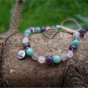 Een armband met lichtroze, grijze, lichtblauwe en paarse kralen.