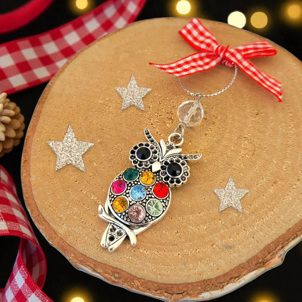 Kerstboomhanger uil met gekleurde steentjes en rood-wit geruit strikje.