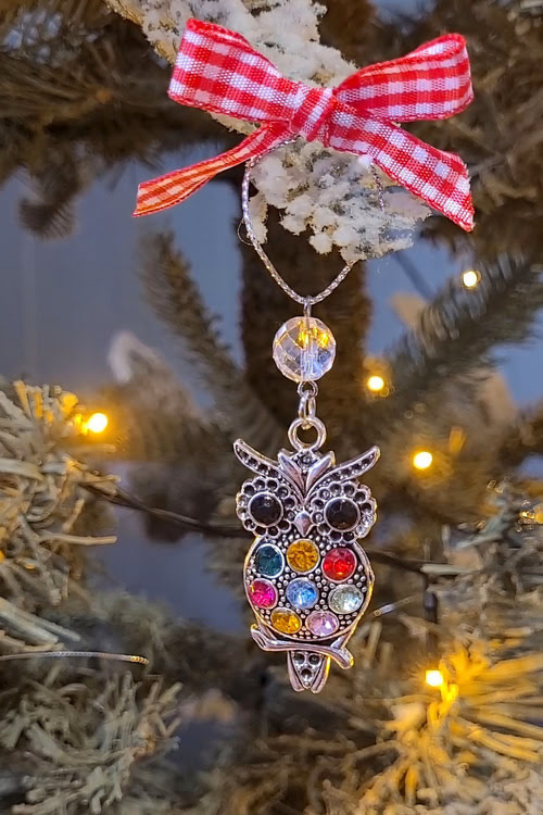 Kerstboomhanger uil met gekleurde steentjes en strikje in boom.